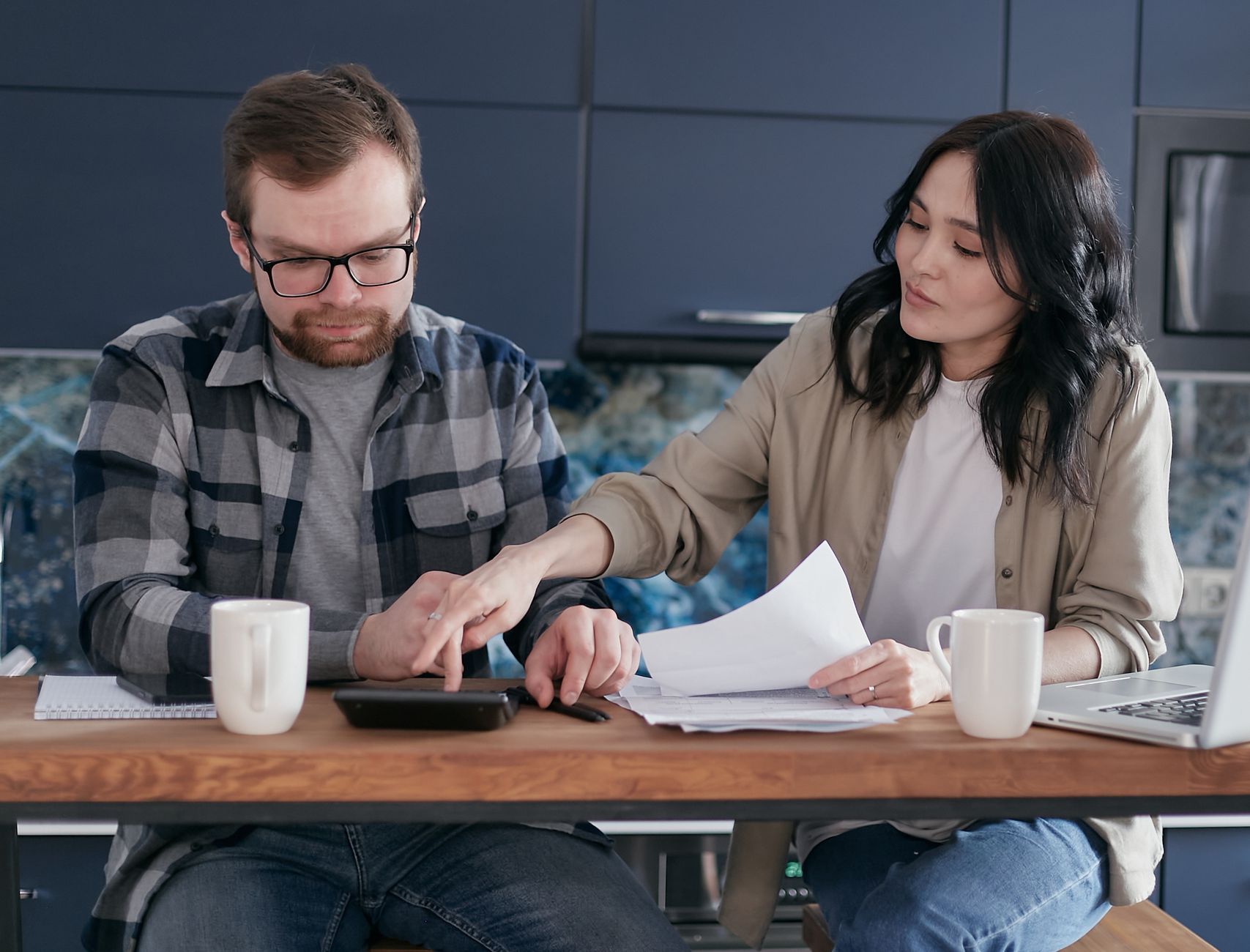 A couple working on their finances together at home, showing teamwork and collaboration. — 3 tips to help your business save