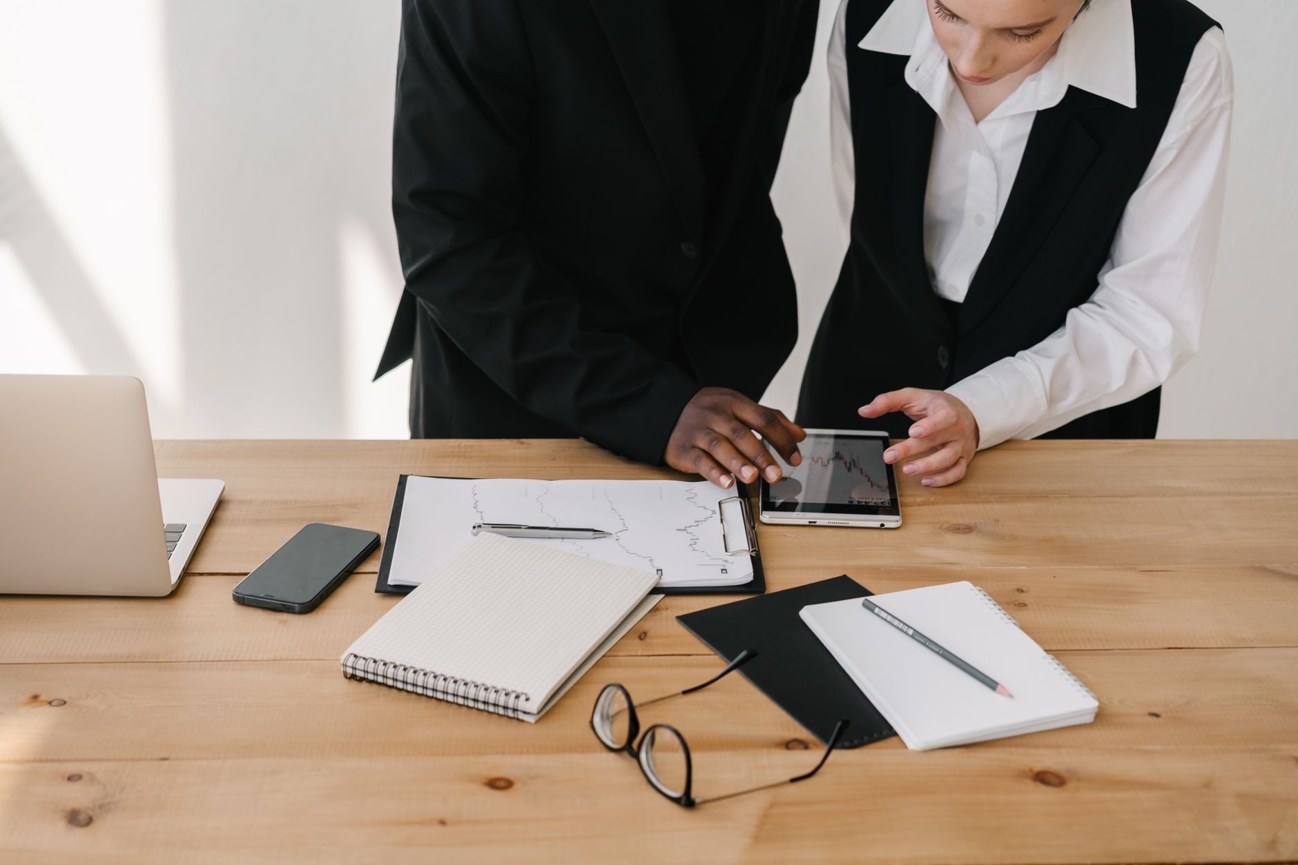 Two professionals collaborating over charts and tablet in a modern office setting. — 5 Tips To Extend The Life Of Your Busine