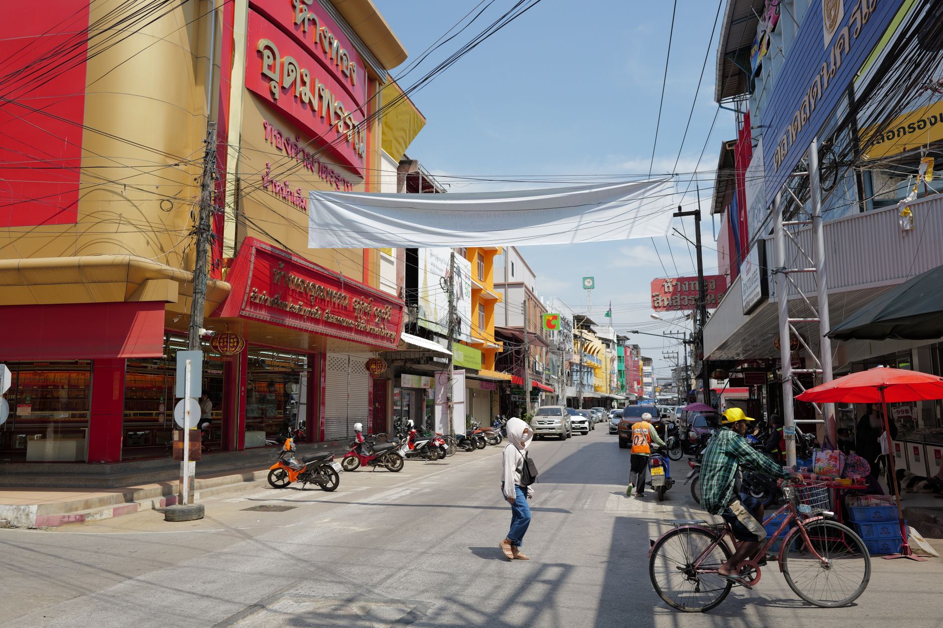 Lively urban street in Thailand with people, shops, and traffic under a sunny sky. — Bags are always required so that you can