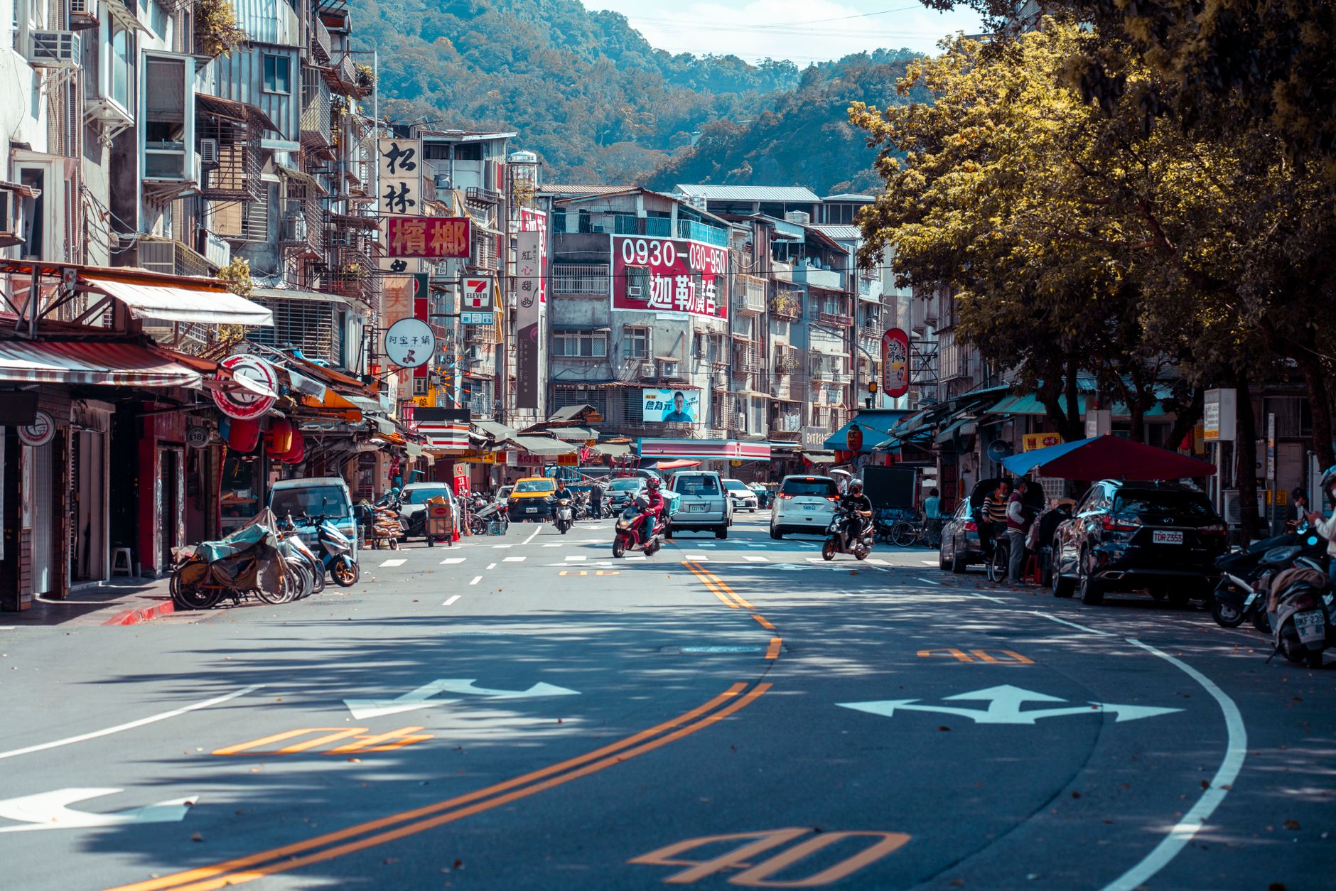 Vibrant urban street scene with shops, vehicles, and mountains in an Asian city. — Commonly Asked Questions About Safeco Auto