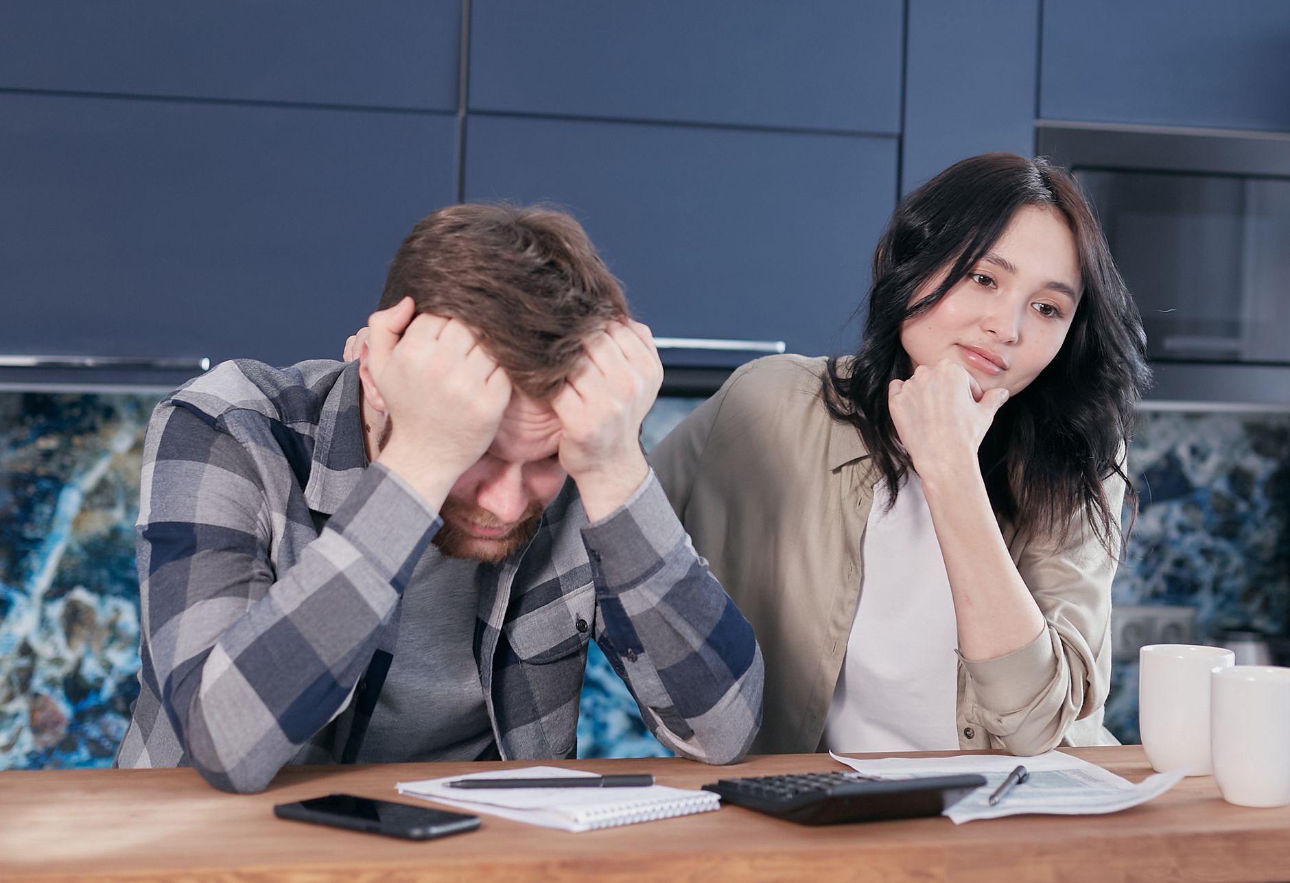A couple looking worried while reviewing financial documents at a kitchen table. — COMPARISON OF ELSS FUNDS WITH OTHER TAX SA