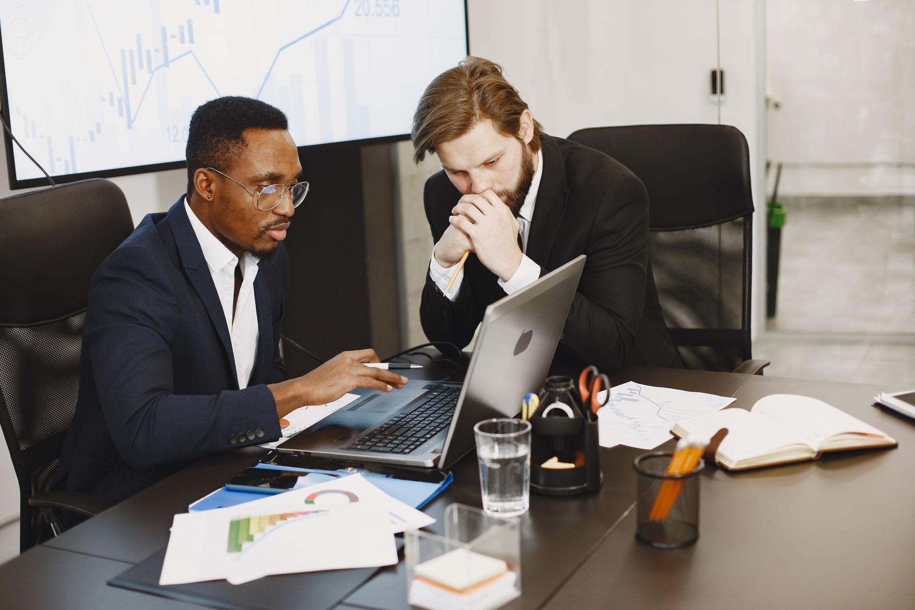 Two businessmen engaged in a strategy meeting with laptops and charts. — Dropship on Facebook Marketplace