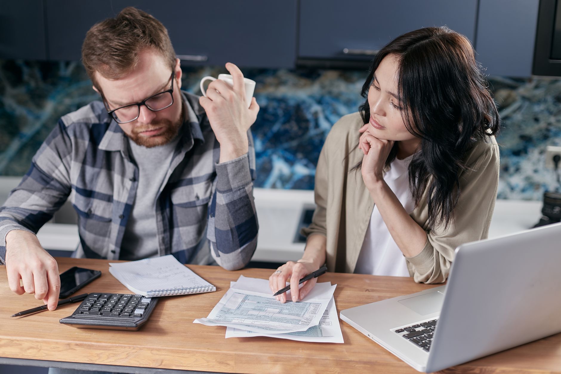 A couple reviews bills and documents on a laptop while discussing household finances. — Earn quick money online, more than Rs