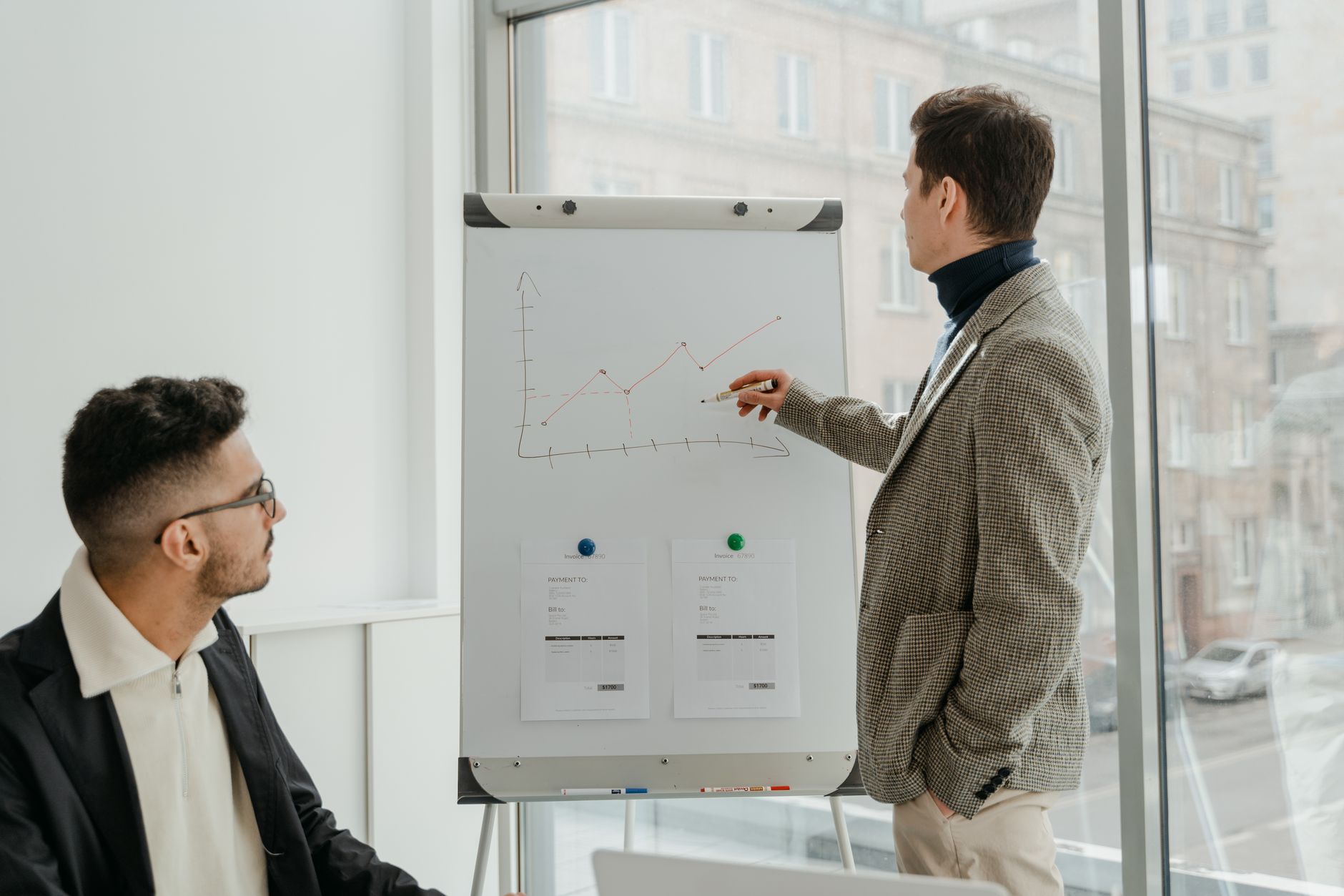 Two professionals examining graphs during an office presentation. — Exploring BTC Regulations and Their Impact on Global Trad