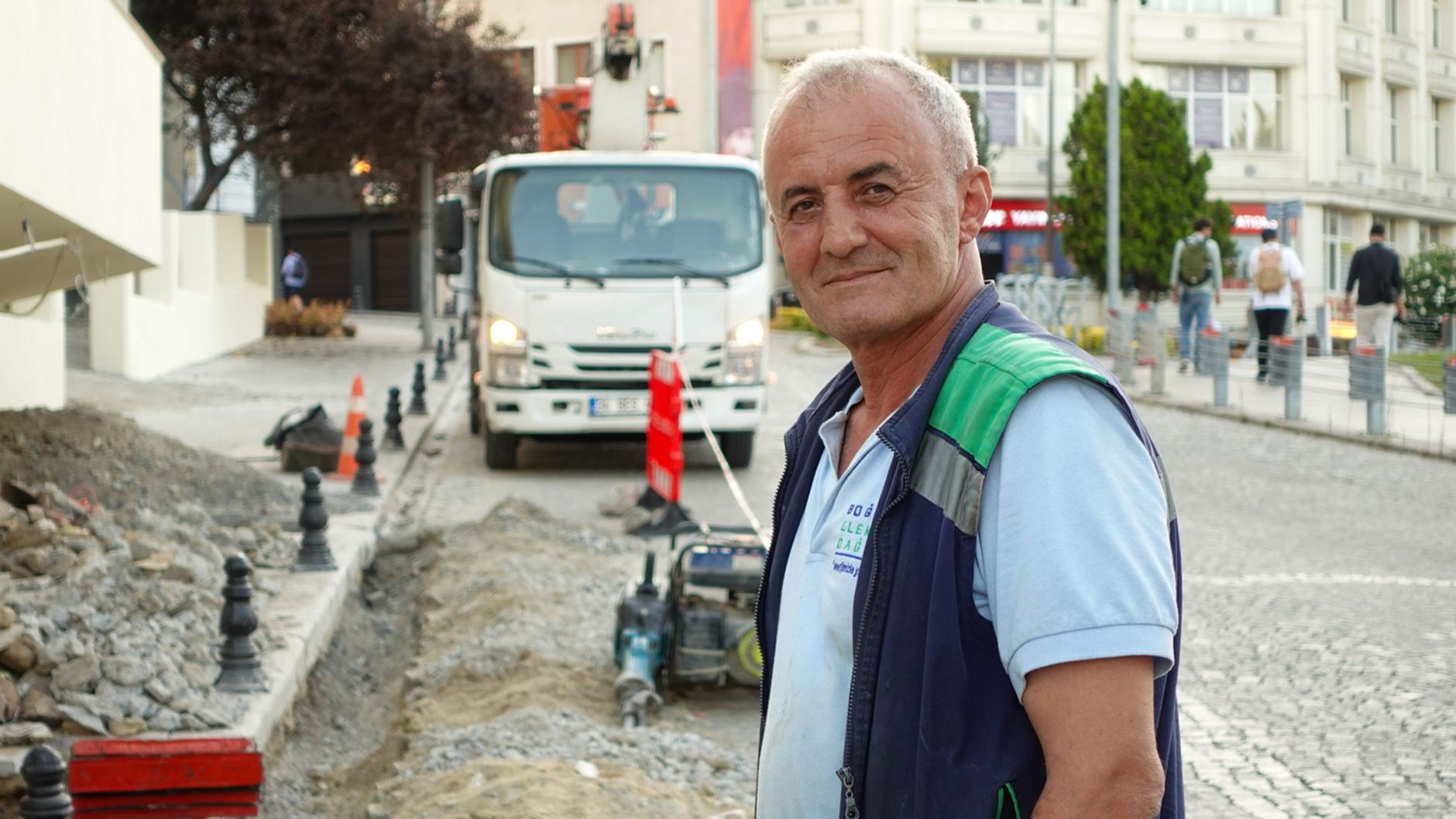 Smiling construction worker on a city street with vehicles and buildings. — Fantasy Cricket vs Live Cricket on Baji999