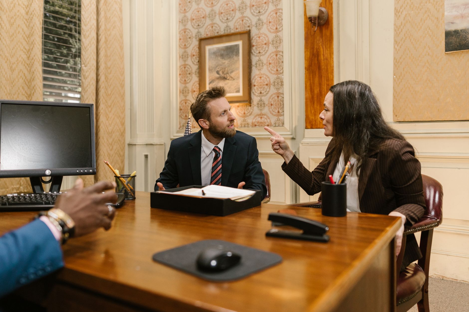 Professionals engaged in a serious discussion inside a law office with a computer on the desk. — Four Common Chest Injuries C