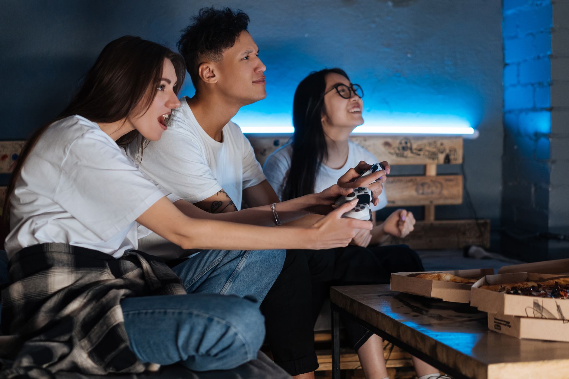 Three friends play video games together indoors, enjoying pizza and fun times. — Gain Confidence in Your Betting Site with Tr