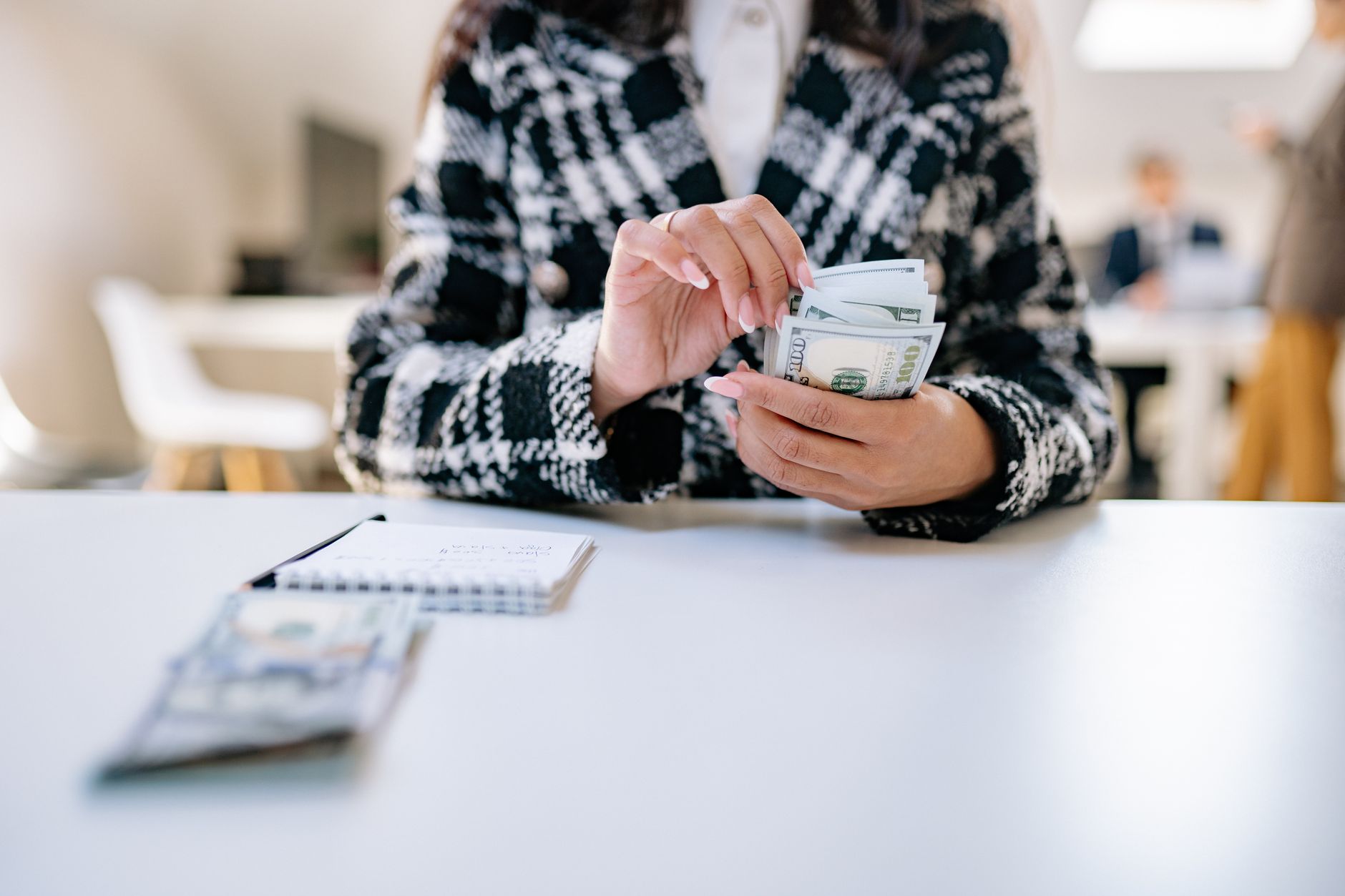 A close-up of a woman counting US dollars in an office environment, symbolizing financial management. — Get the best FD rates