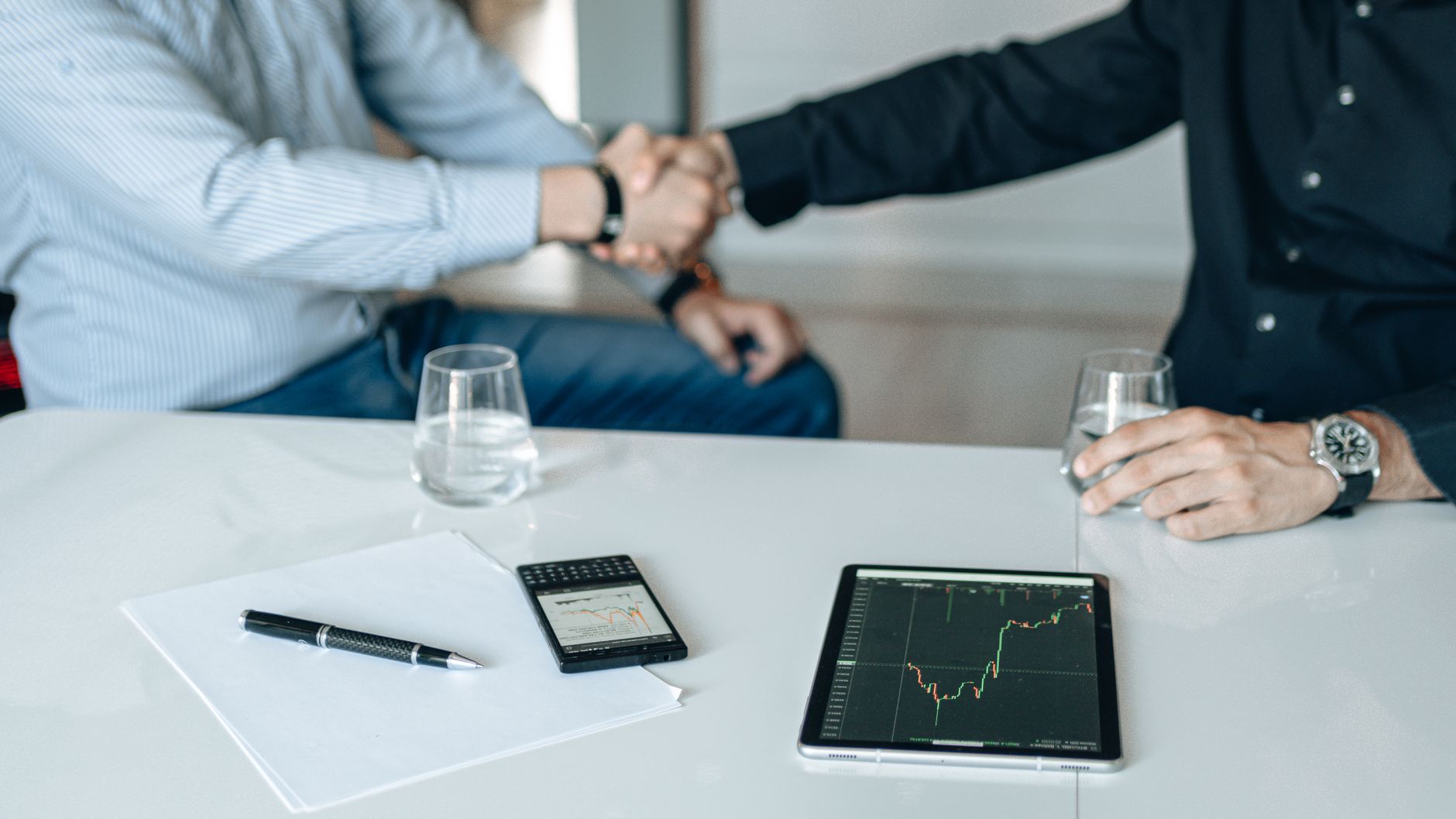 Business meeting with handshake and financial analysis displayed on a tablet. — Guide to Customizing Your MDF Board Cut to Si