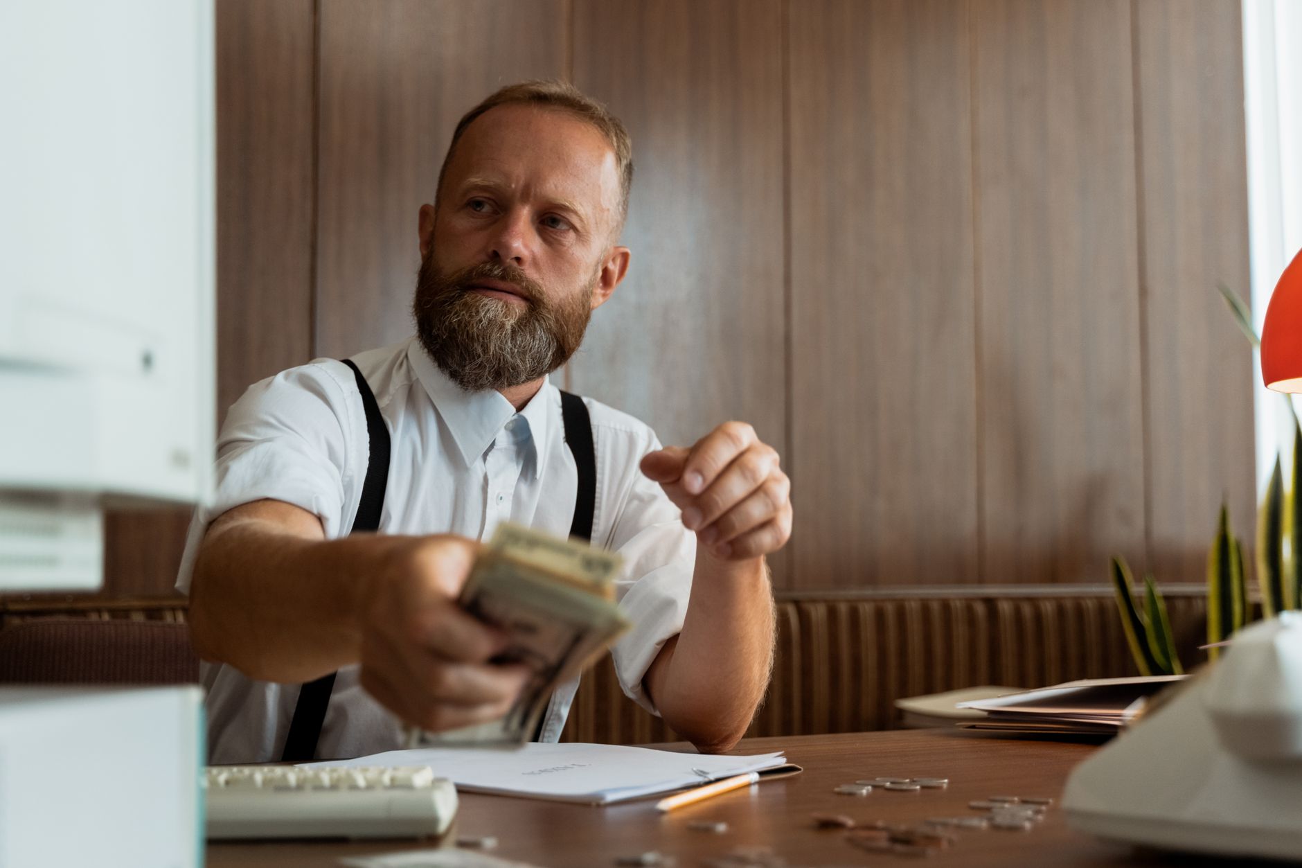 Businessman in a corporate office handling a stack of cash at his desk. — How can you get yourself started in cryptocurrencie