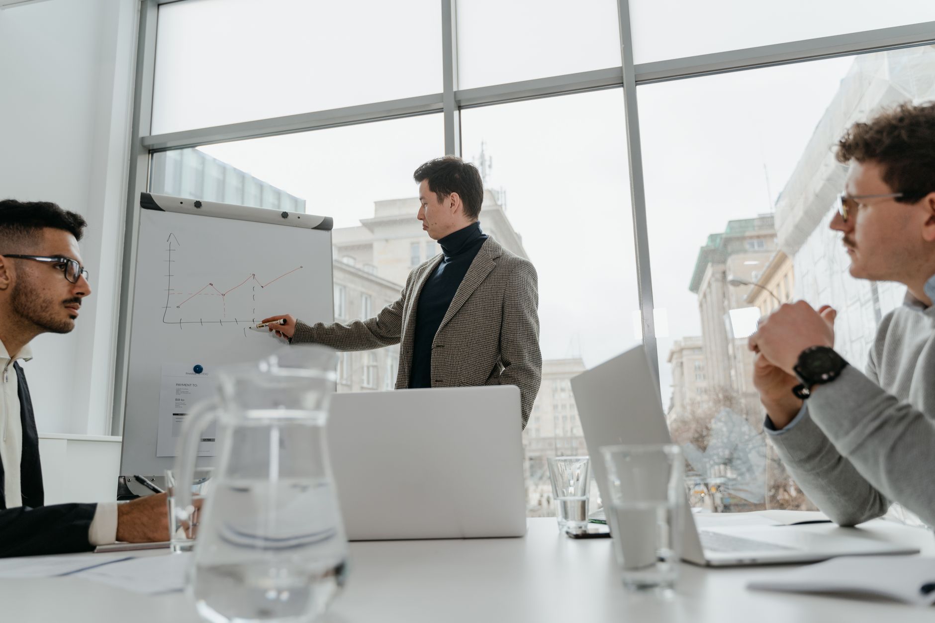 Professionals engaged in a collaborative business meeting with charts and laptops in a modern office setting. — How to Avoid