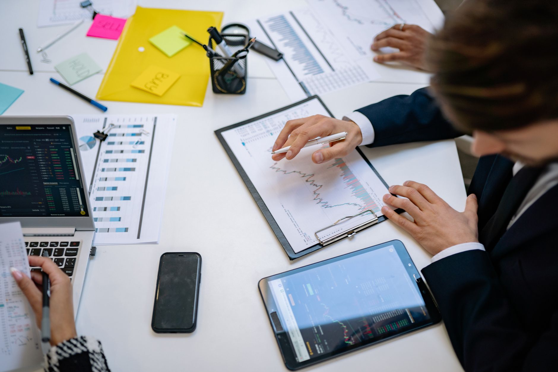 Team reviewing financial charts and digital data on tablets in an office setting. — How to create a good brand based on marke