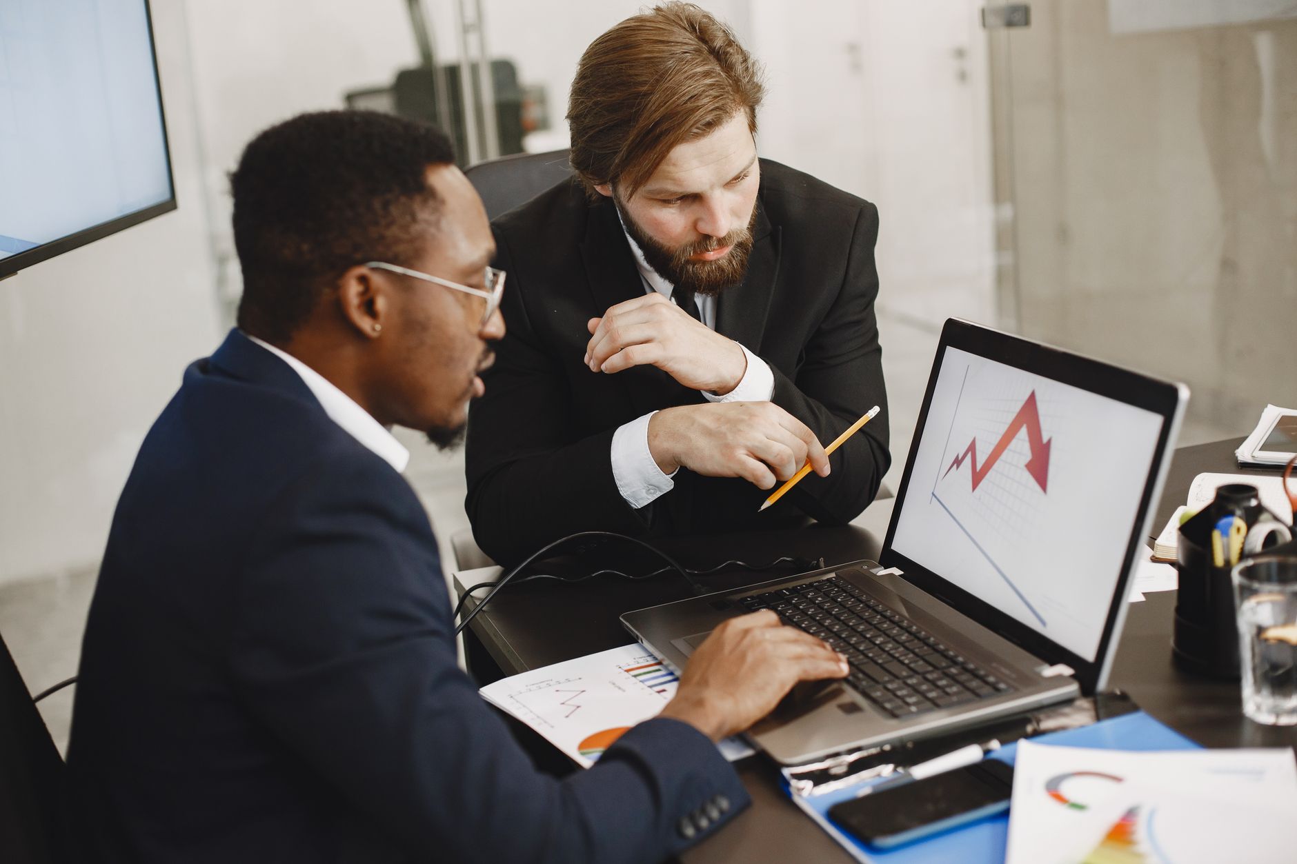 Two business professionals discuss marketing data on a laptop in a modern office. — How To Find Best Laptops for Editing-The