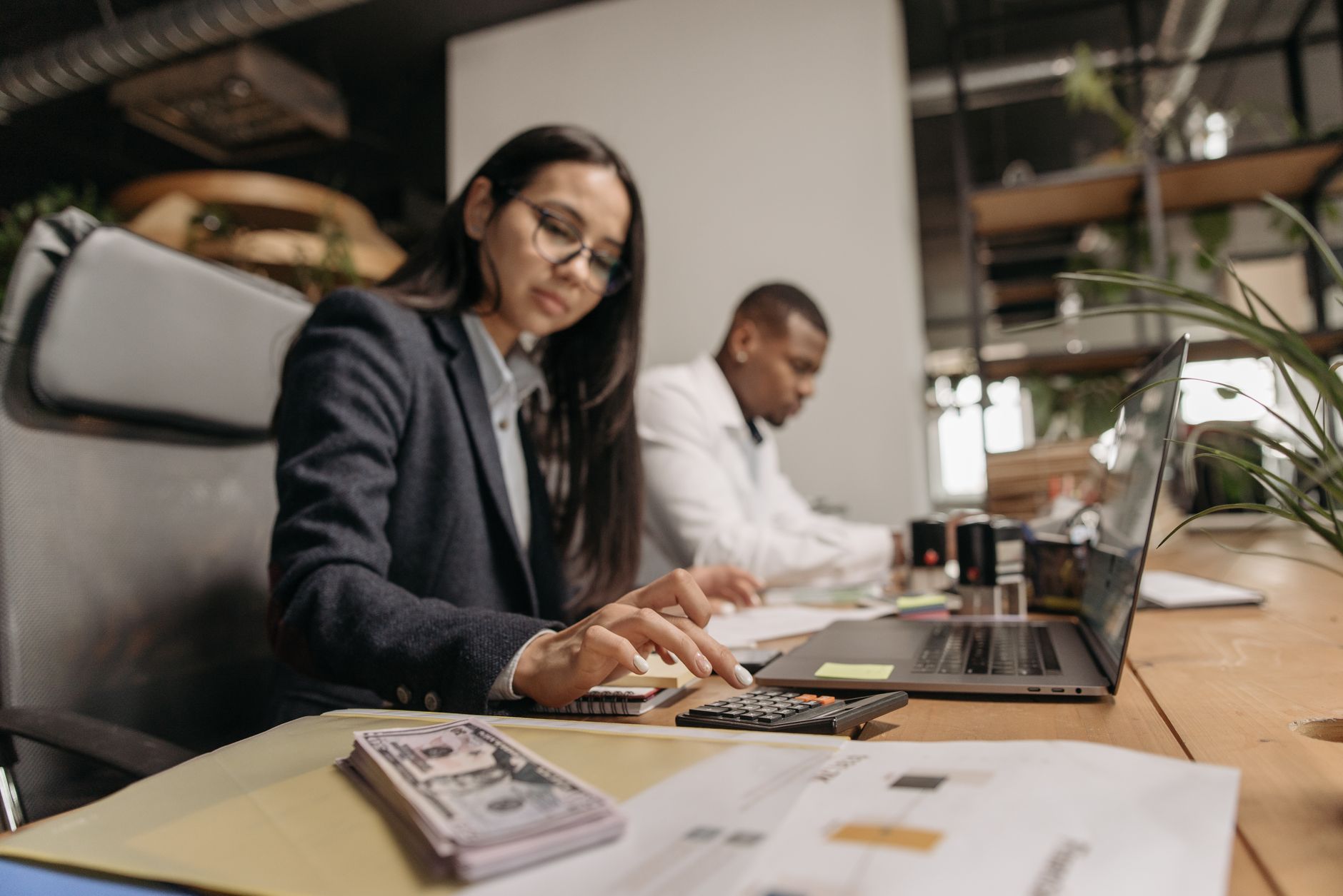 Two business professionals collaborating with a laptop and calculator in a modern office. — How to Maximise the Rental Value