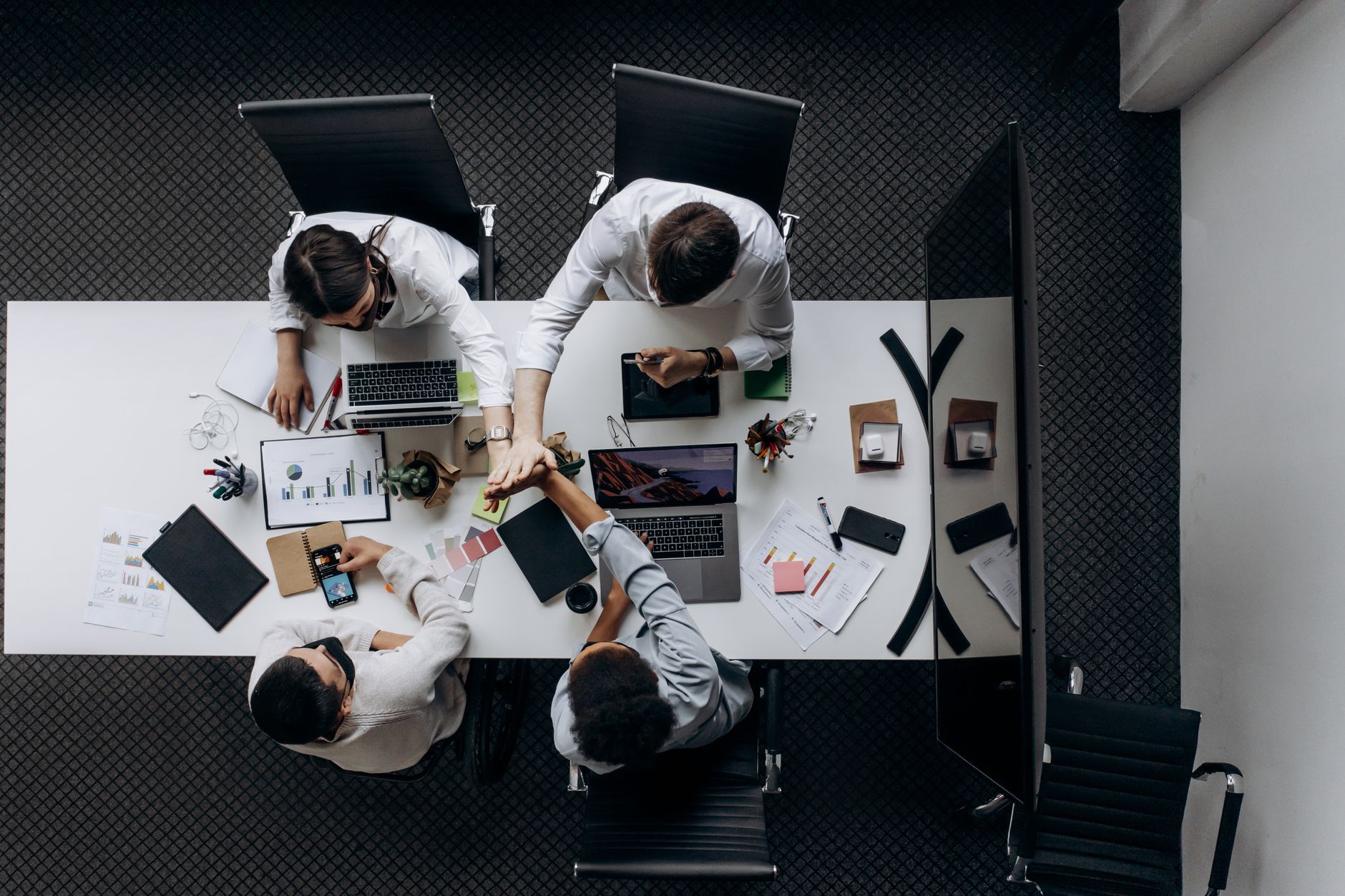 High angle view of colleagues collaborating around a conference table in a modern office setting. — How to work with digital