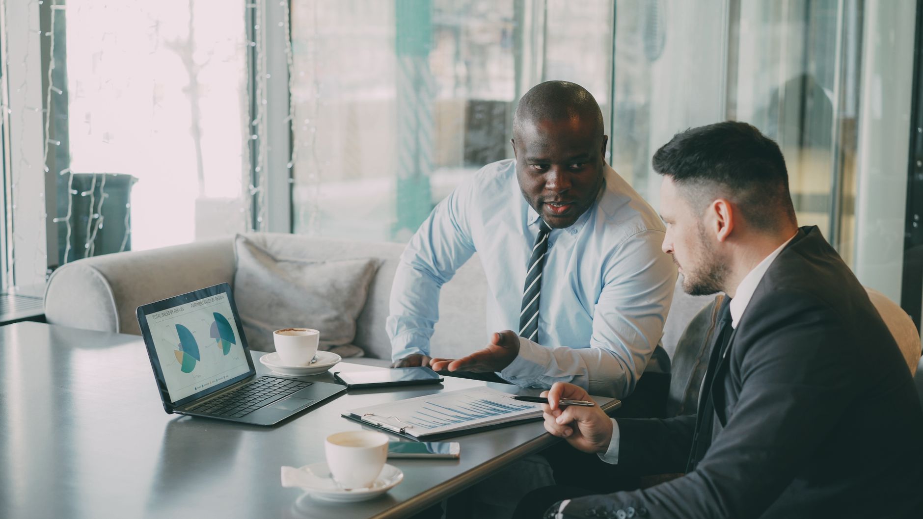 Two businessmen discussing data at a cafe while enjoying coffee. — How will Modifications Affect My Car Insurance?