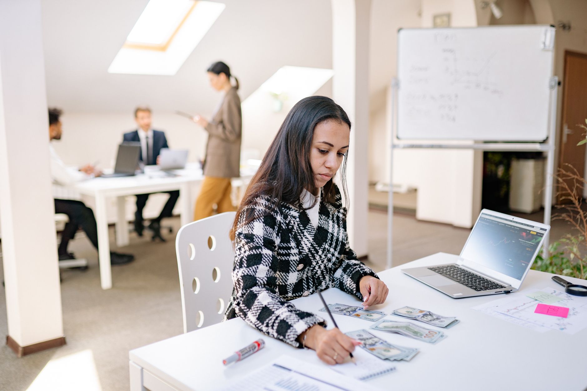 Focused businesswoman reviewing financial documents and currency in a modern office setting. — Loans and the Right Managing C