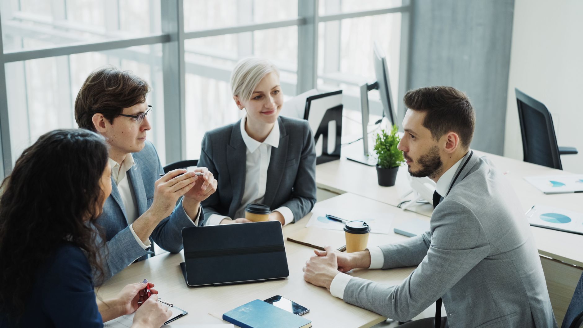 Group of professionals having a discussion in a modern office setting with natural light. — Promote Your Online Jewelry Busin