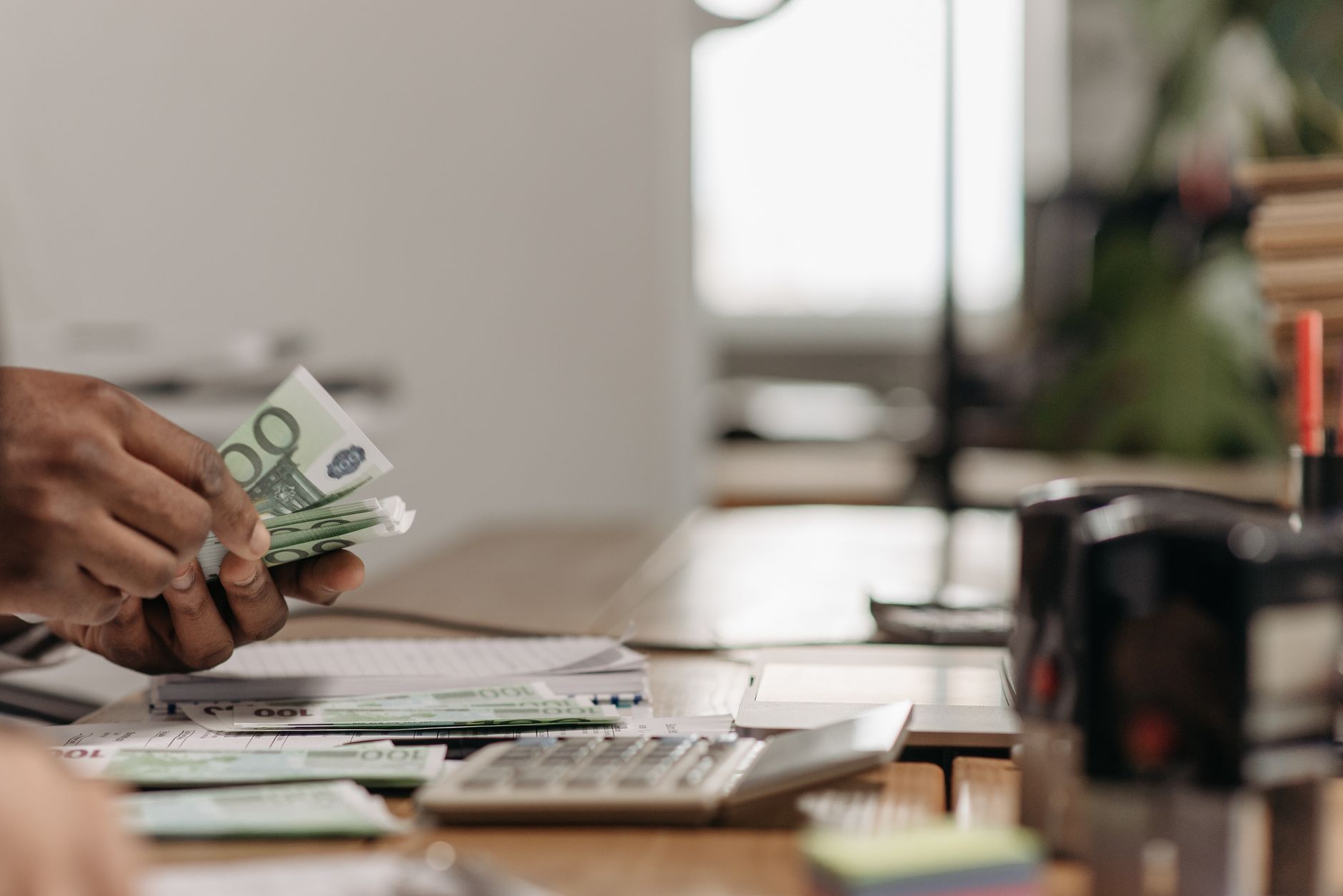 Close-up of hands counting euro bills at an office desk with a calculator. — Strategy with Divergences in Binary or Forex Opt