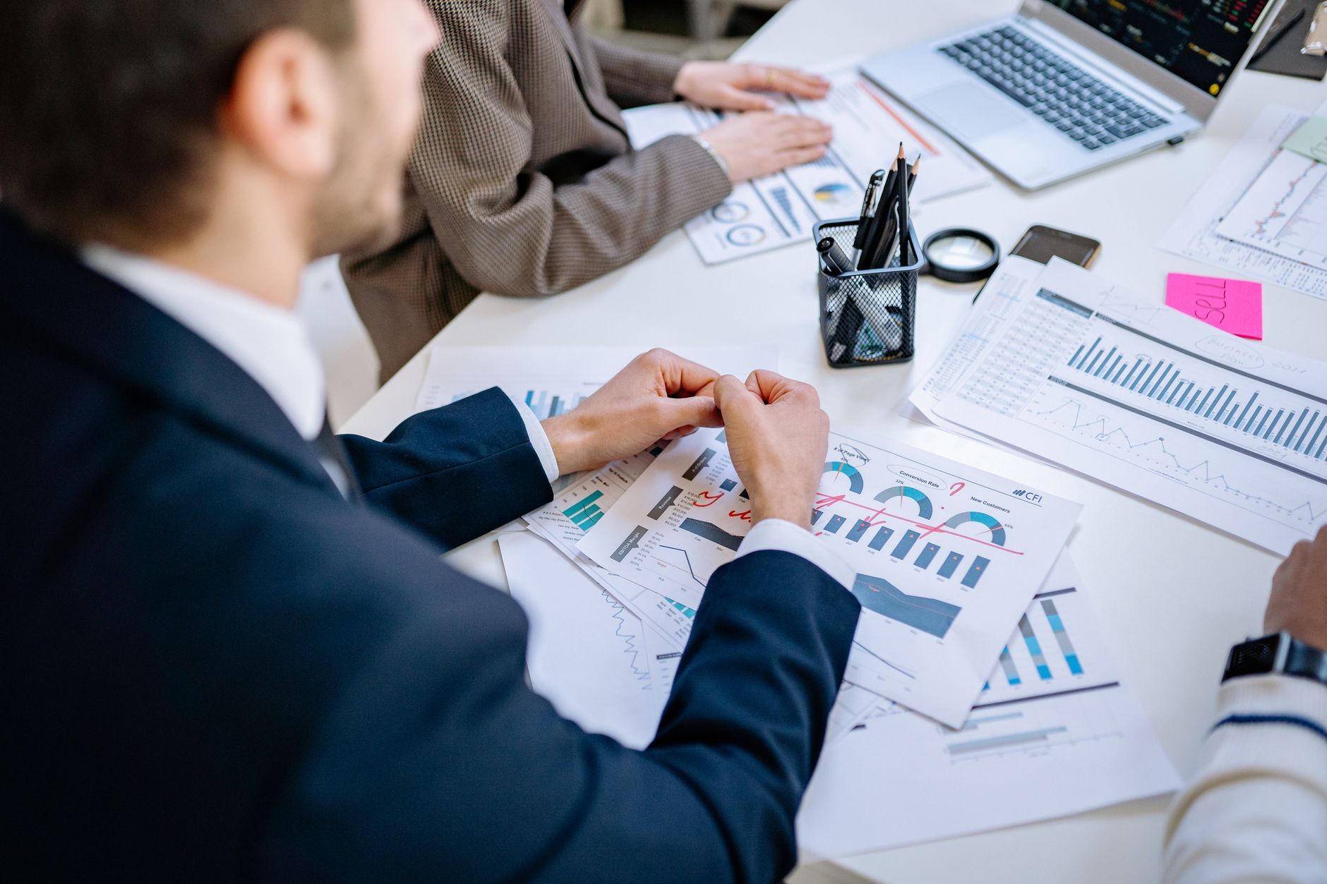 Business team analyzing financial graphs at a meeting table, fostering collaboration in an office environment. — Get