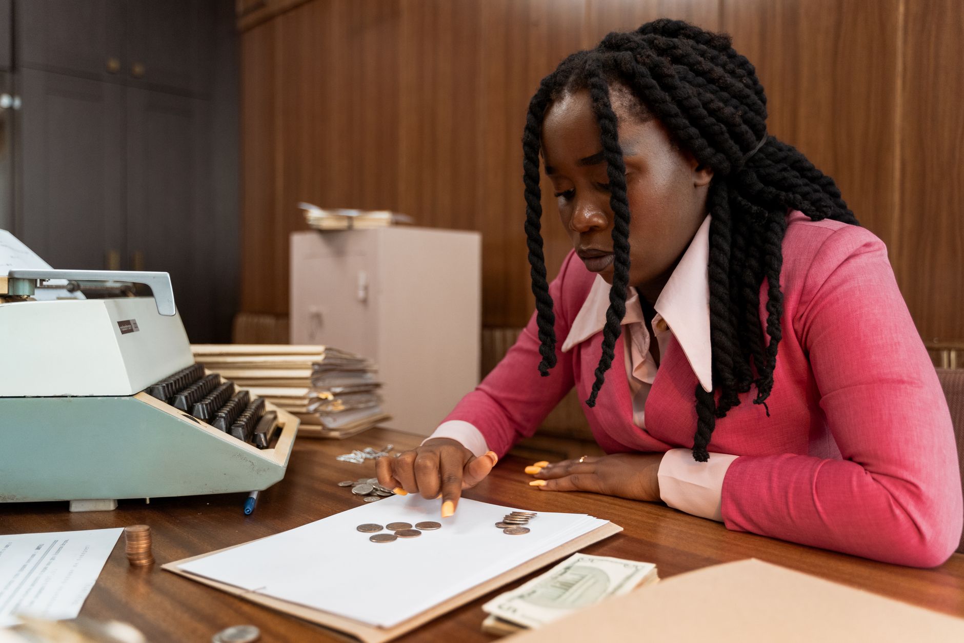 A businesswoman in vintage attire counts coins in a retro office setting. — The Kind of Loan You Can Get As Assured