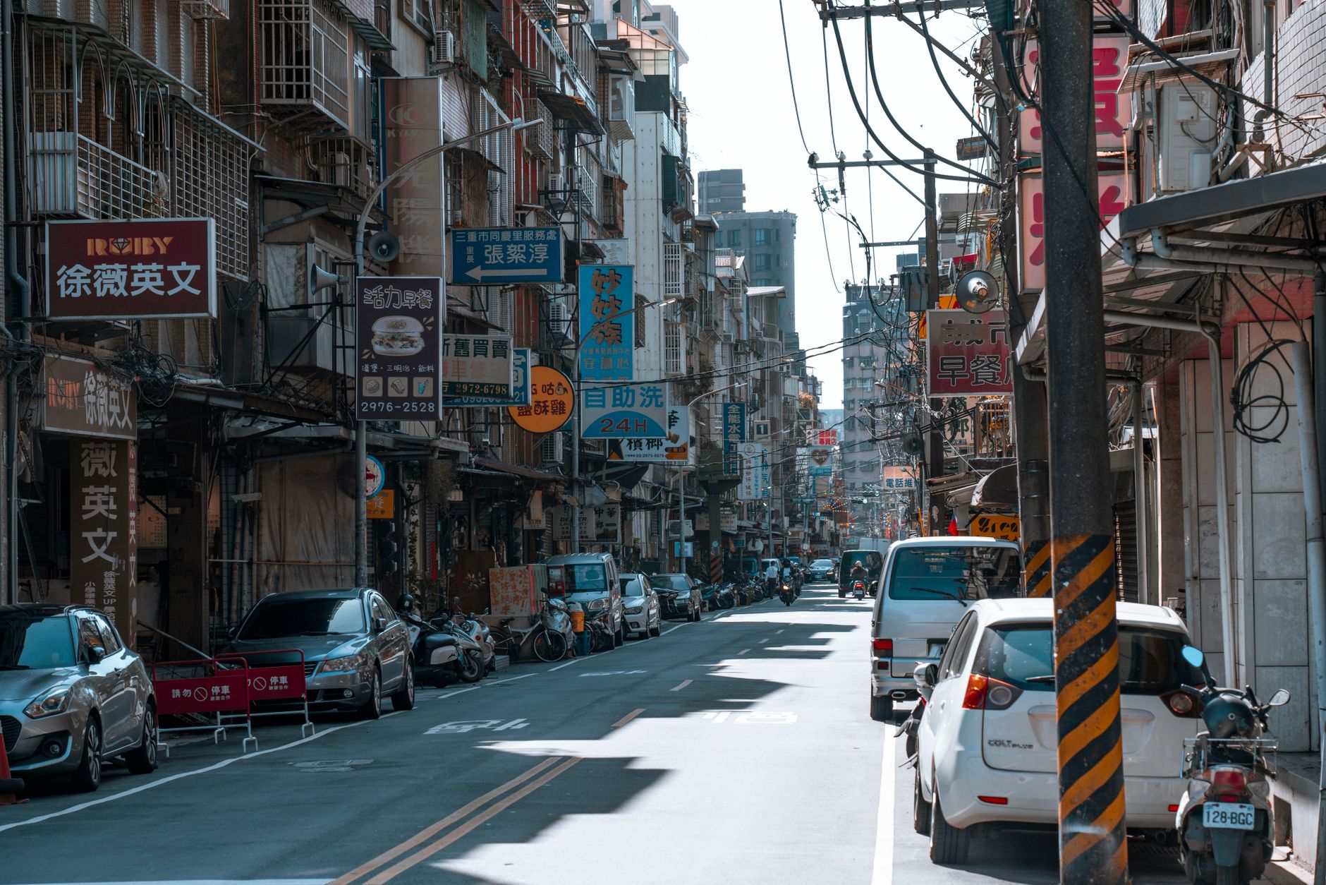 A busy street lined with cars and various colorful business signs on a sunny day. — The Role and Importance of E-commerce Dev