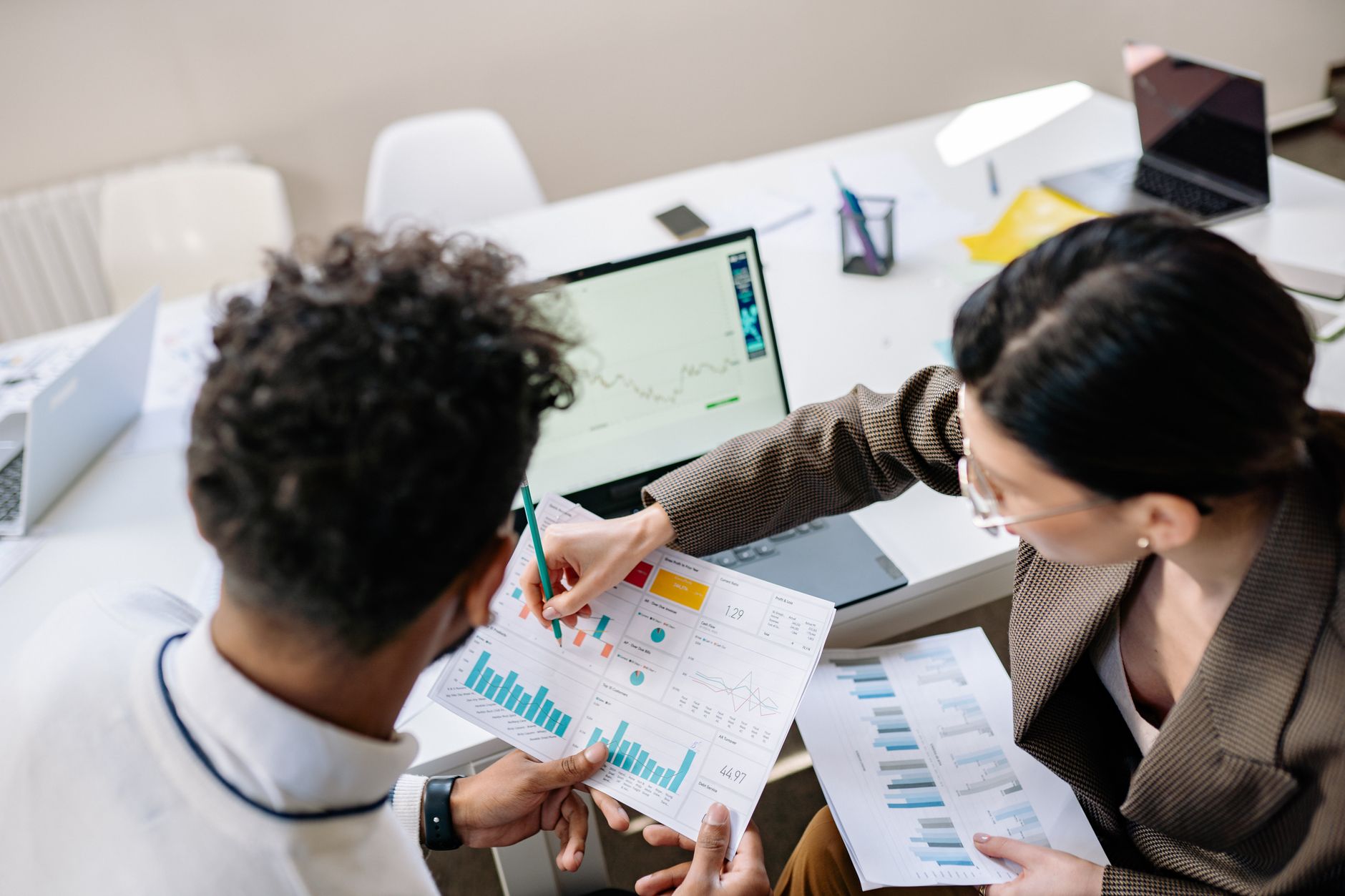 Two colleagues in a meeting room discussing financial charts and graphs on a laptop and paper. — Things You Should Know Befor