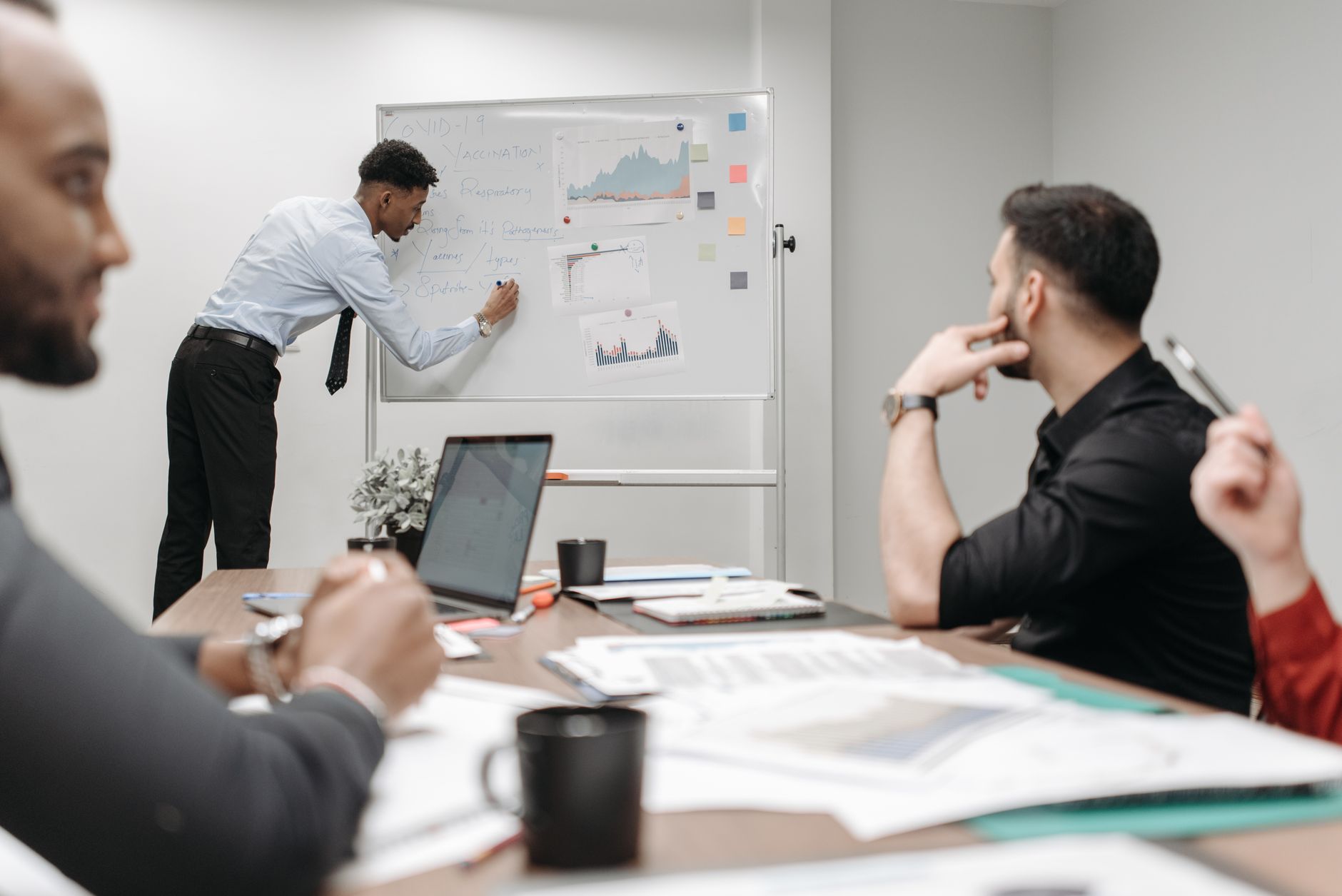Colleagues in a business meeting discussing data and strategies at the office. — Tried & tested methods to launch large-scale