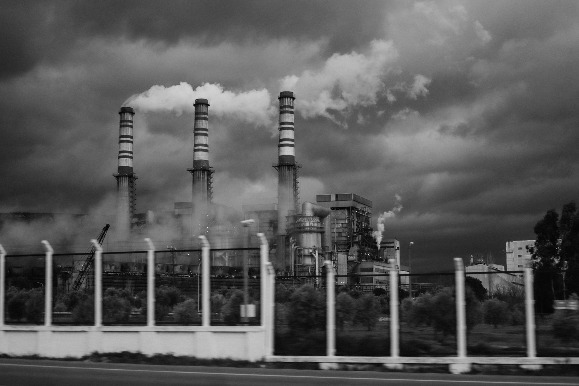 Black-and-white photo of a factory emitting smoke, highlighting industrial pollution. — UAE Military/Civilian Industrial Base