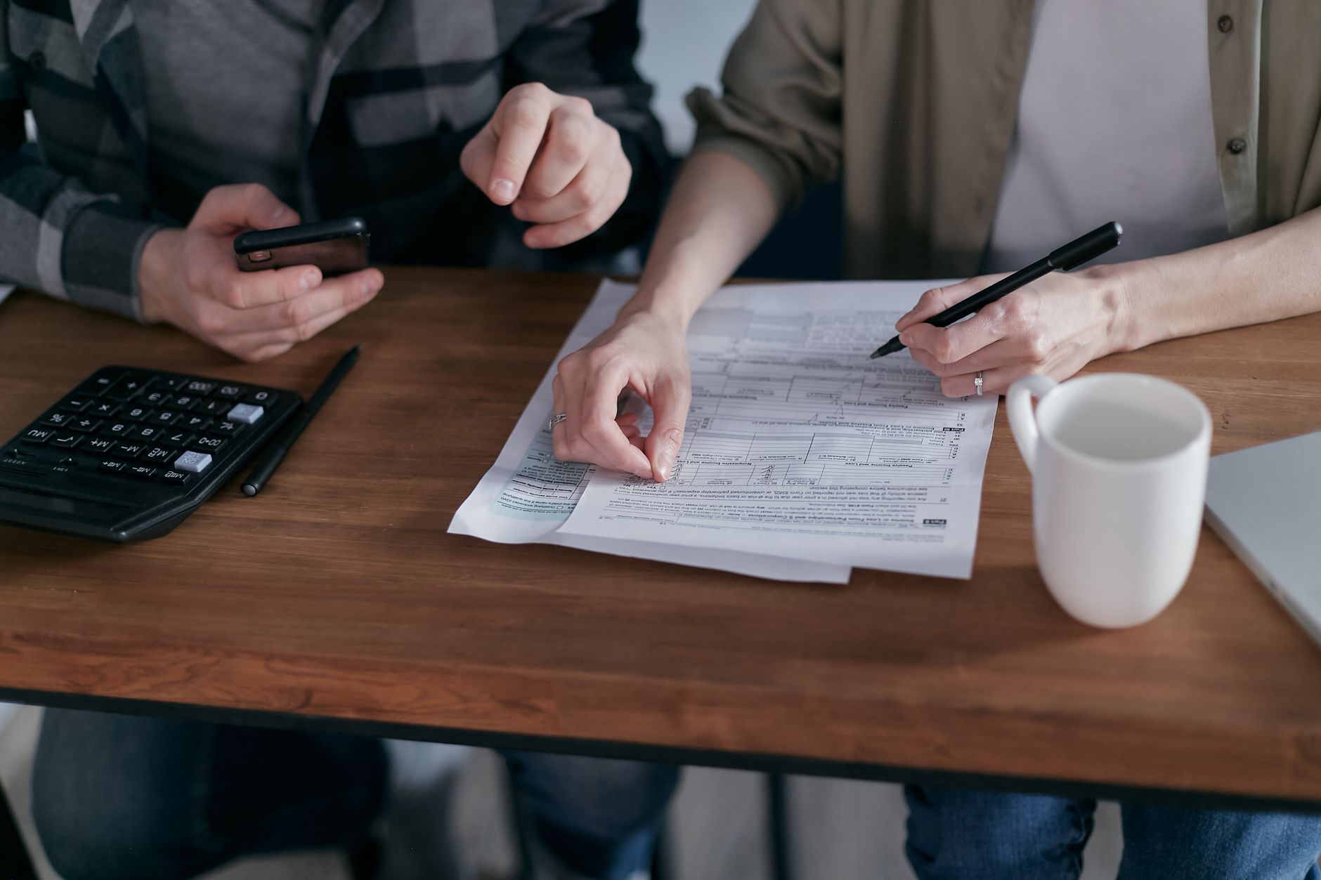 Couple managing finances at home with a calculator, smartphone, and documents. — Vehicle Finance - What You Must Know About D