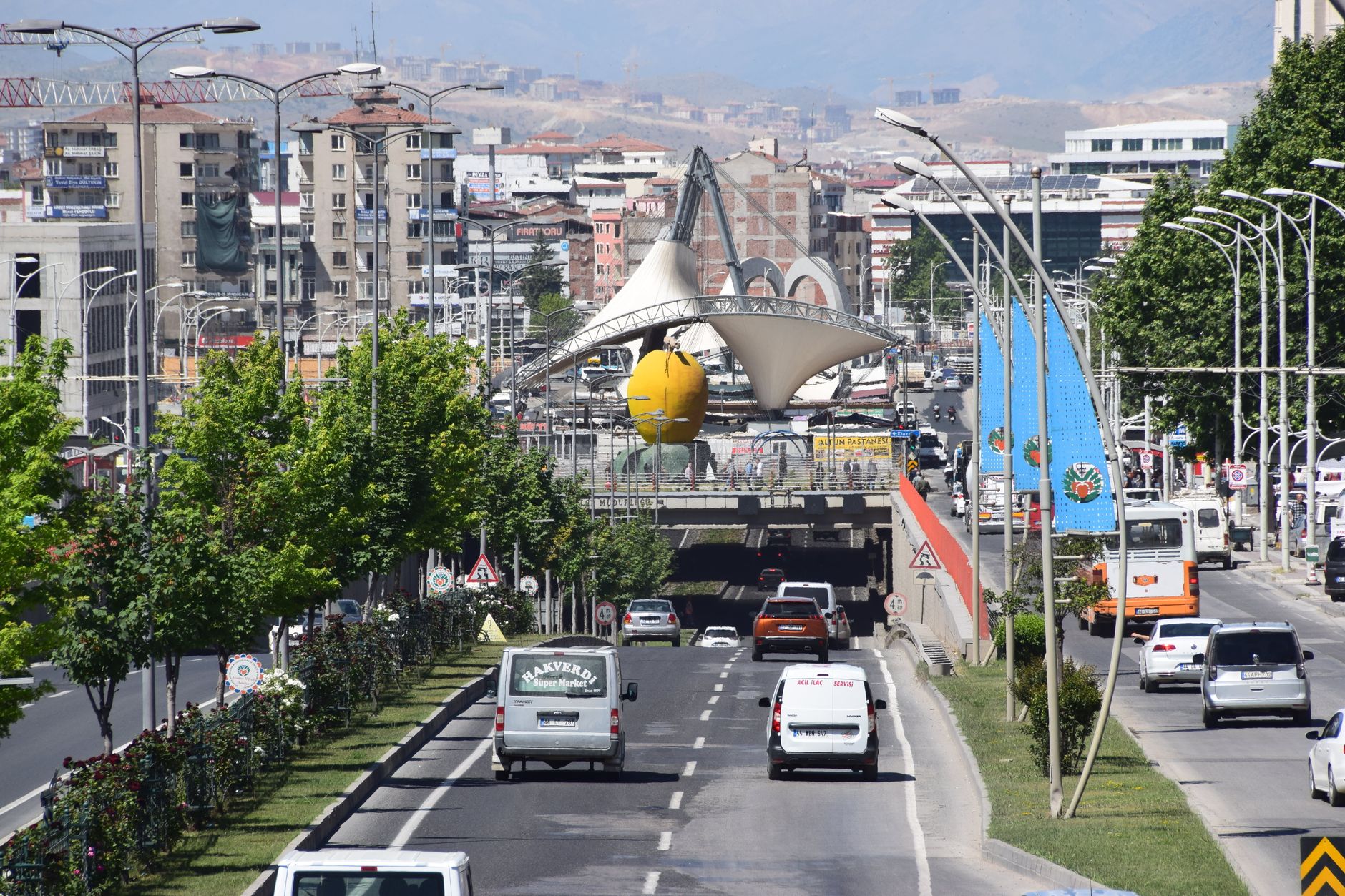 A bustling street scene in Malatya, Turkey featuring iconic apricot sculpture and cityscape. — What are display tables? Who s