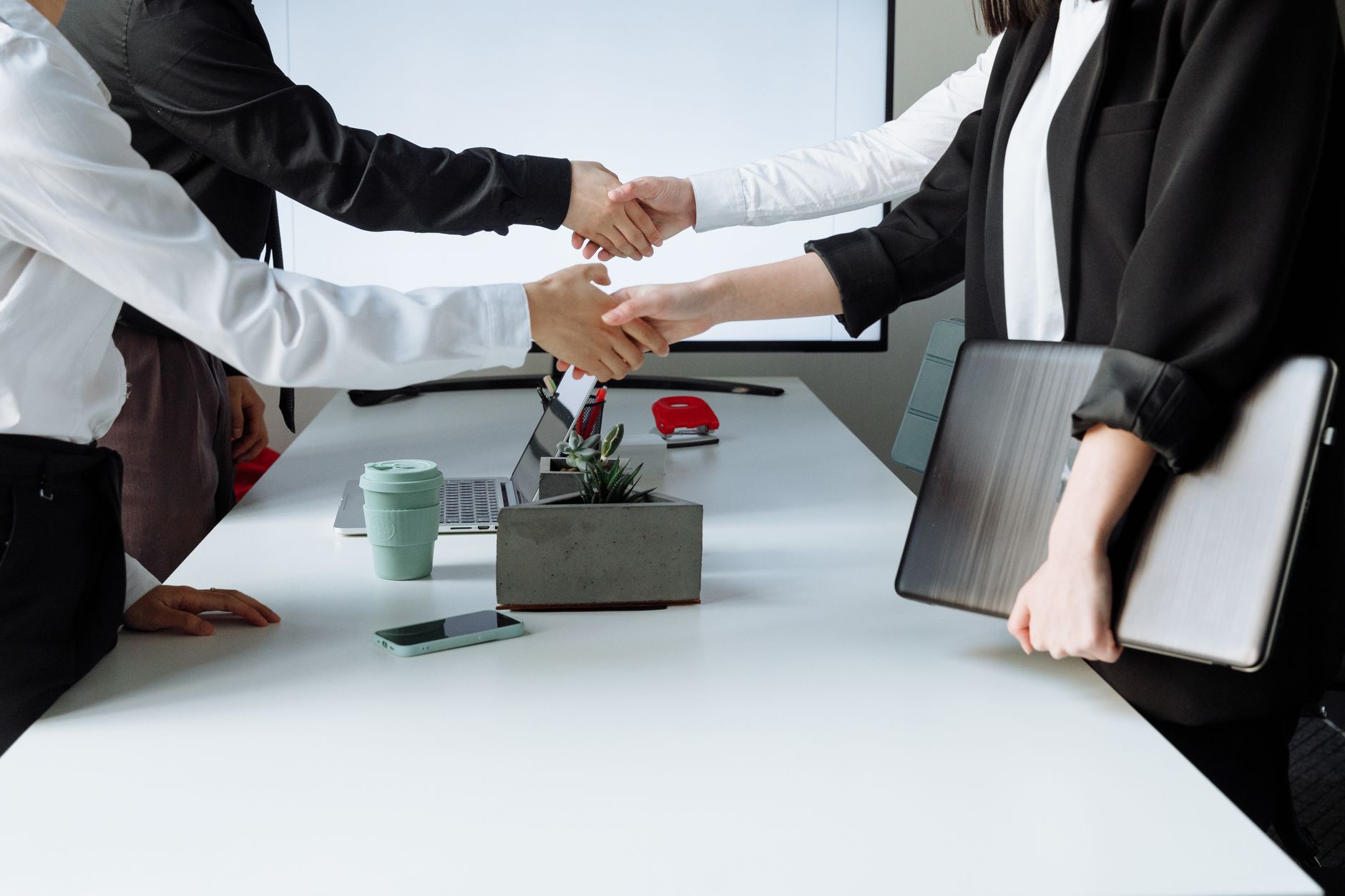 Professionals sealing a deal with a handshake across a conference table during a business meeting. — What Are Essential Cover