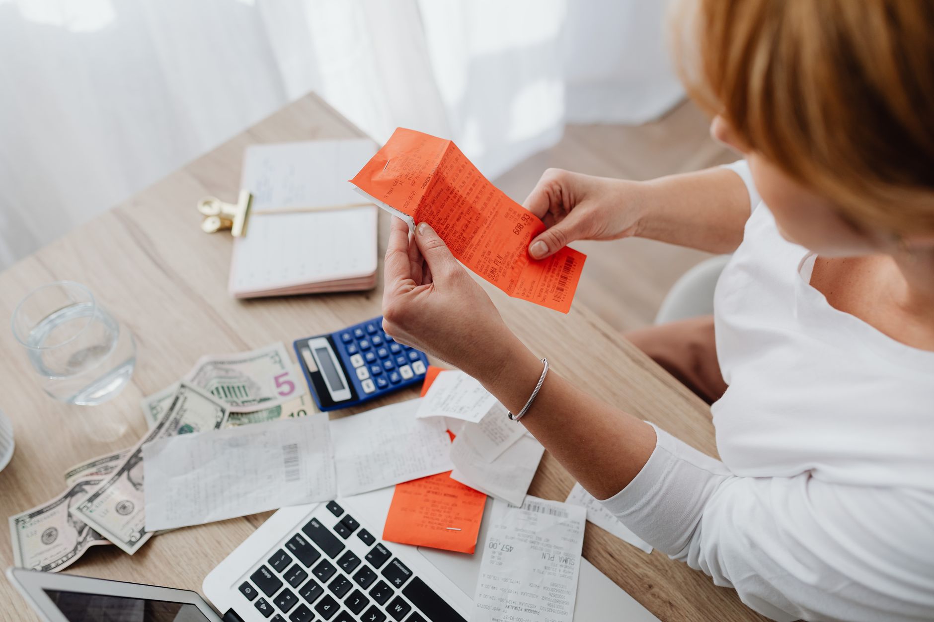 Woman using calculator and receipts at home office desk for finance management. — What are hybrid funds and how do they work?