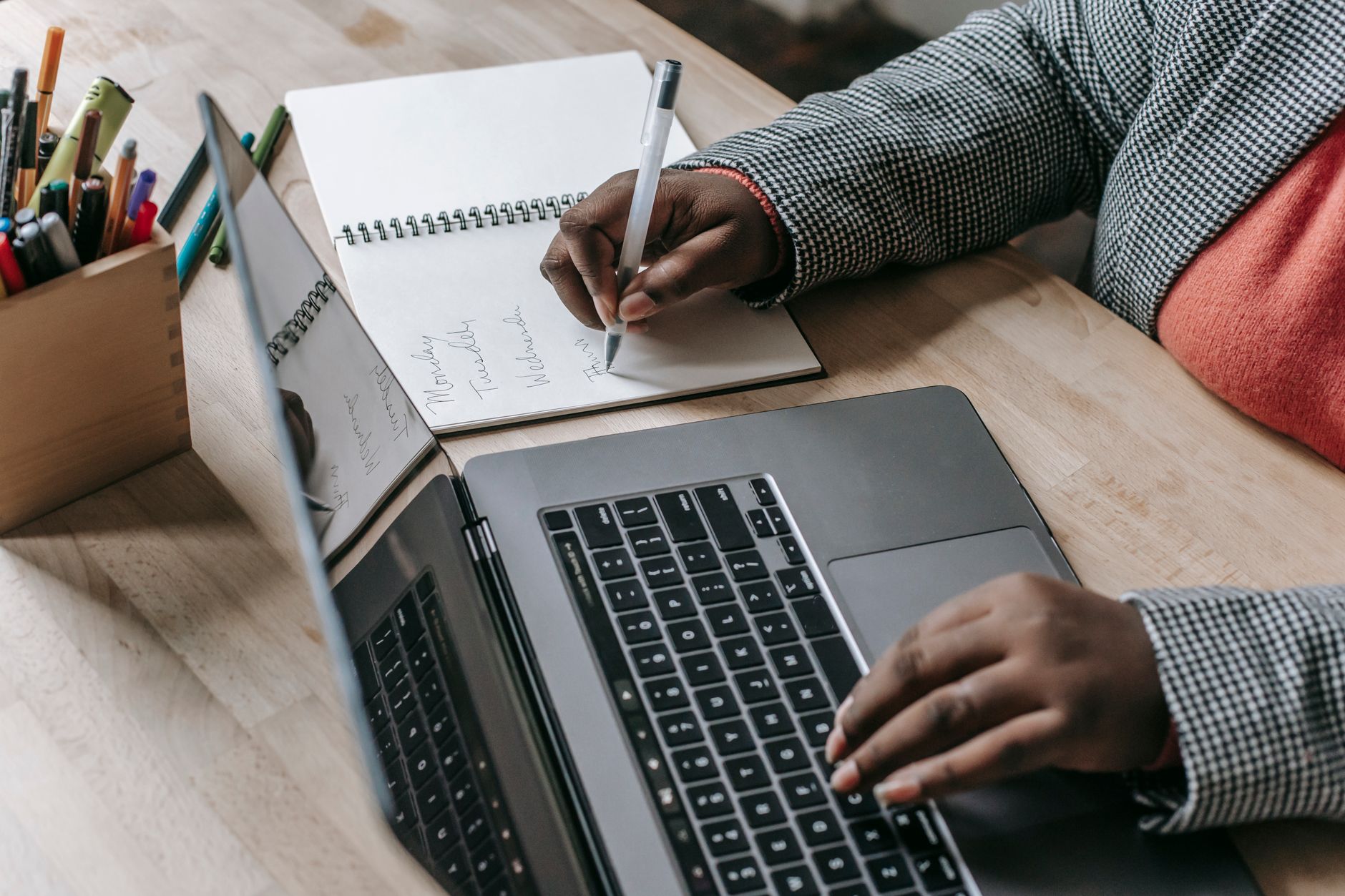 Crop unrecognizable African American female in formal wear writing notes in notepad while working on laptop — What are some d