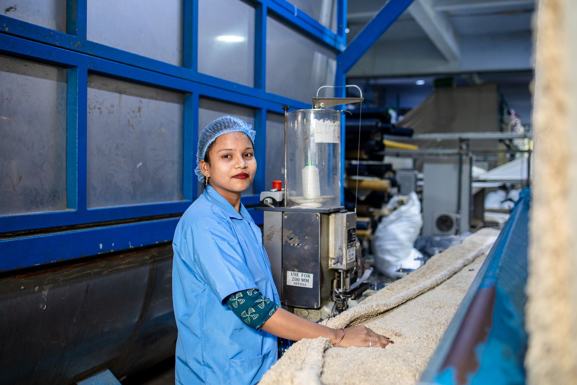 A woman in a blue uniform operates a machine in a textile factory, ensuring quality and precision. — What is warehouse distri