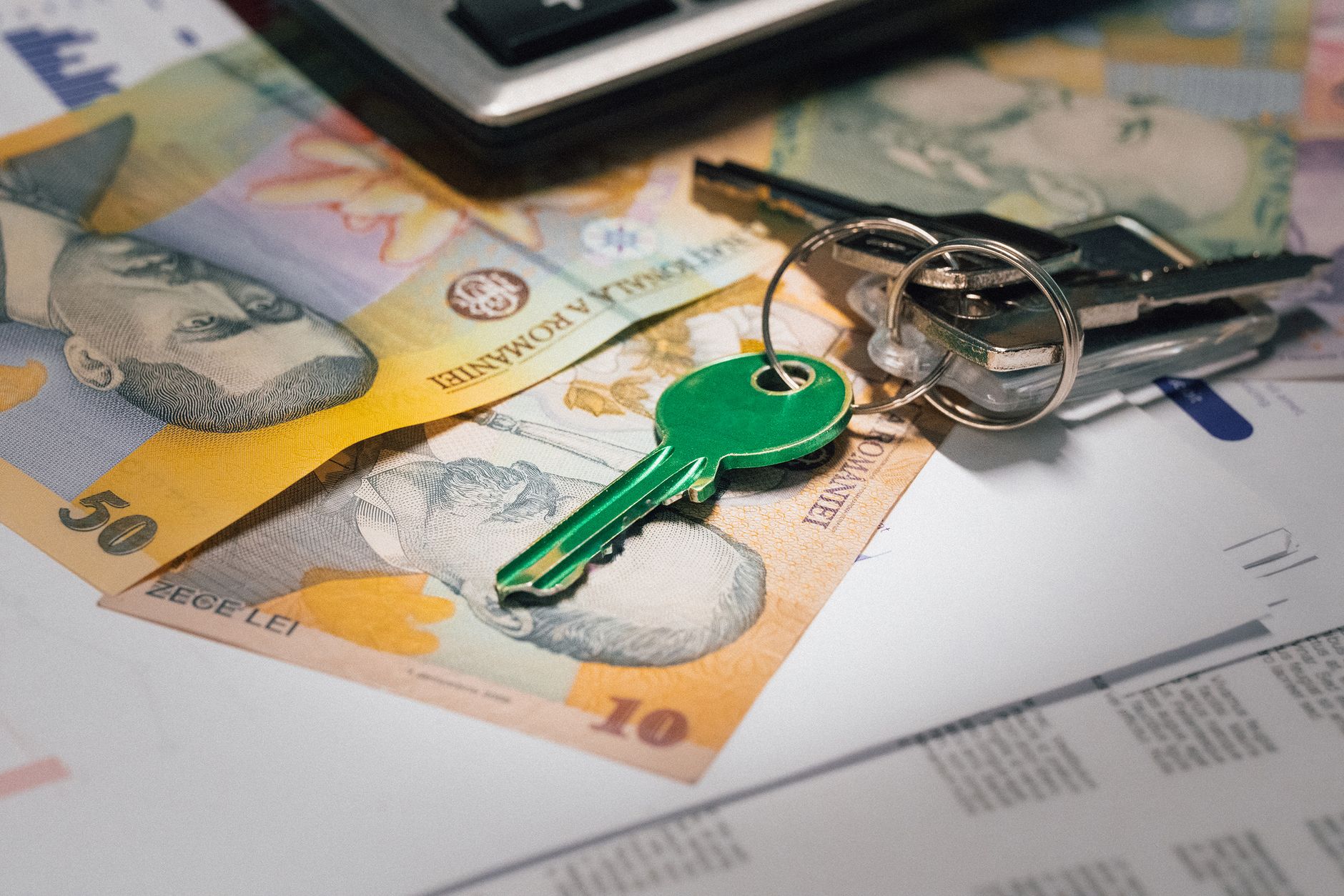 Close-up of Romanian banknotes with a set of keys, representing real estate investment and financial planning. — What Should