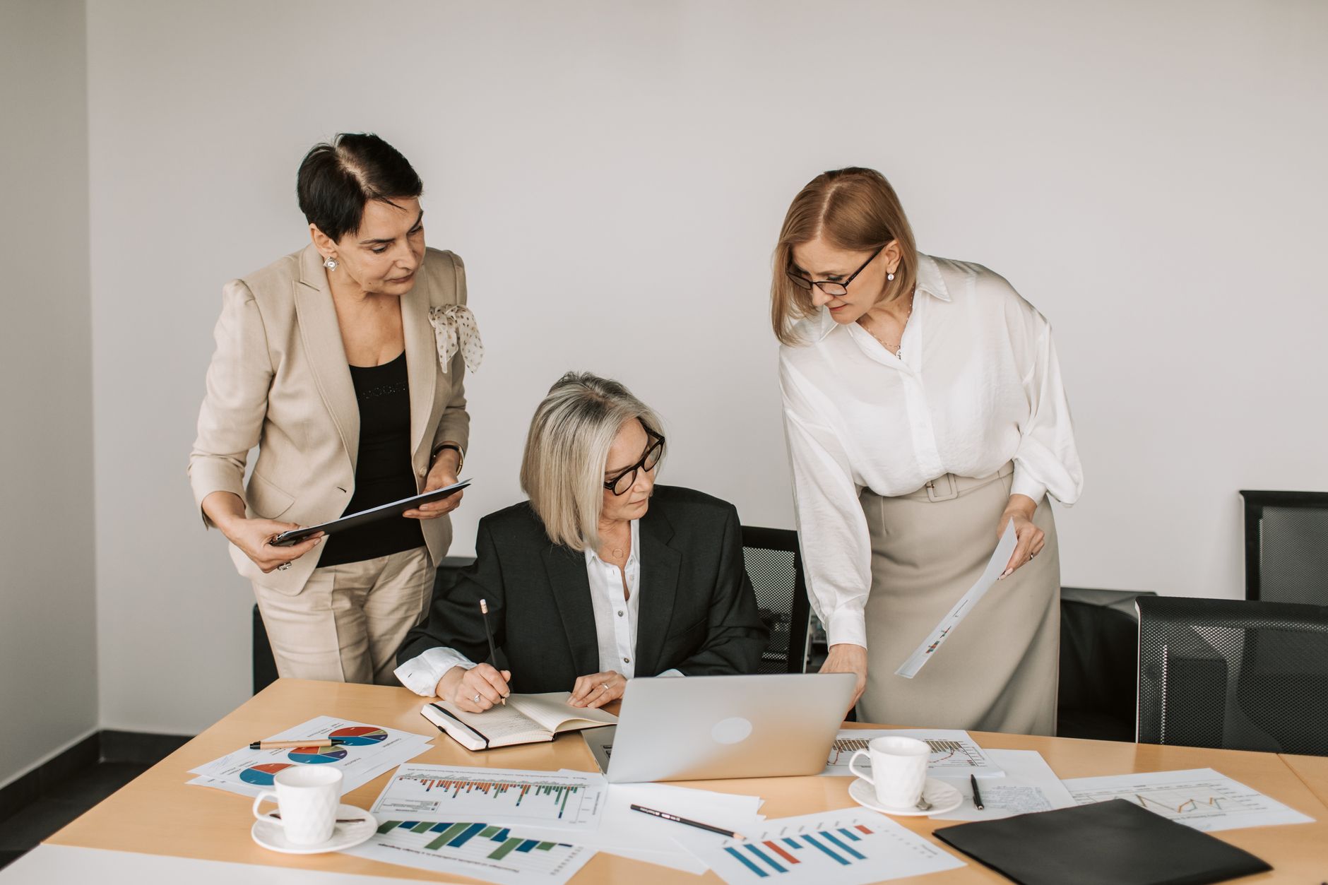 Three businesswomen discussing documents during a meeting in a modern office setting. — Why Choose Term Insurance Over Tradit