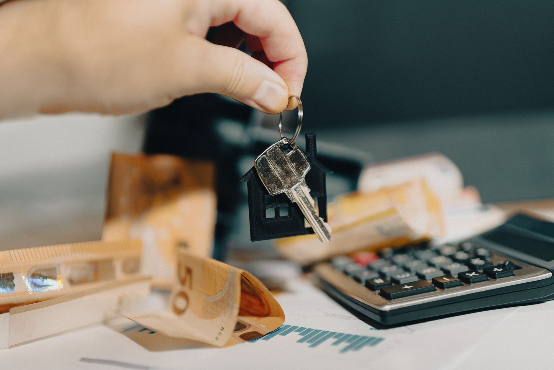 Close-up of a hand holding keys over euros and calculator, symbolizing real estate purchase. — Why Choose Term Insurance Over