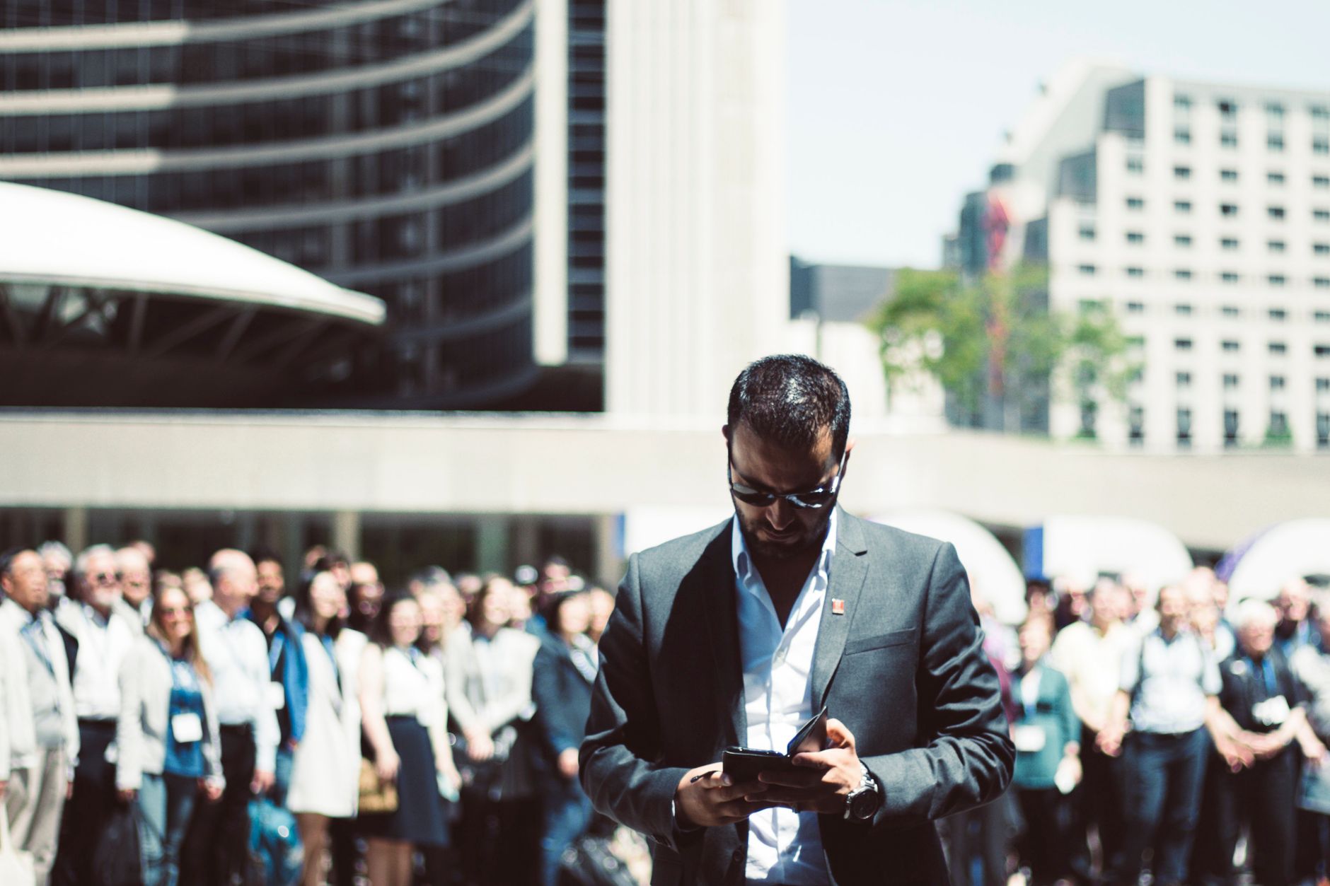Focused businessman using tablet in a bustling crowd in Toronto's busy urban setting. — Will working from home affect my fina